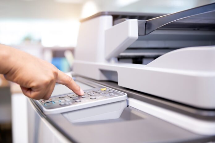 Close up hand of office man press the button on the copier. Outsourcing de impressão cresce com seletividade em 2026